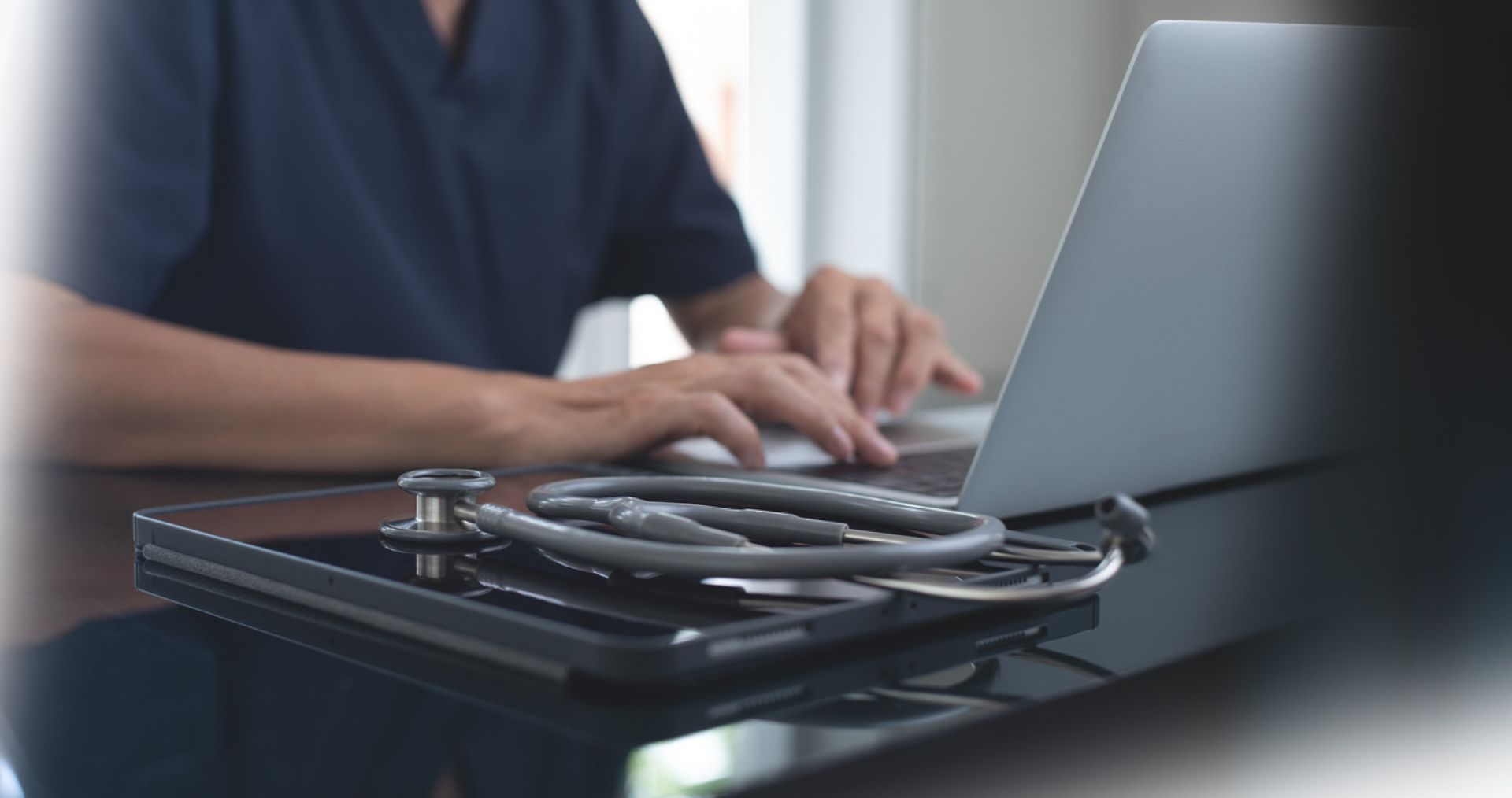 Smiling dentist holding a book, sitting in a dental office with equipment around.